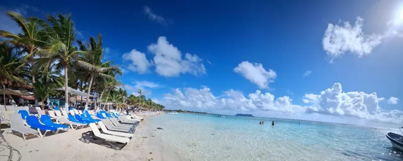 Panoramic view of Mahahual beach with blue loungers and turquoise water