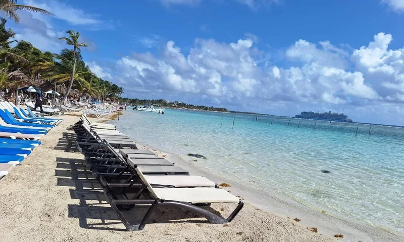 Row of sun loungers on the white sand of Mahahual beach