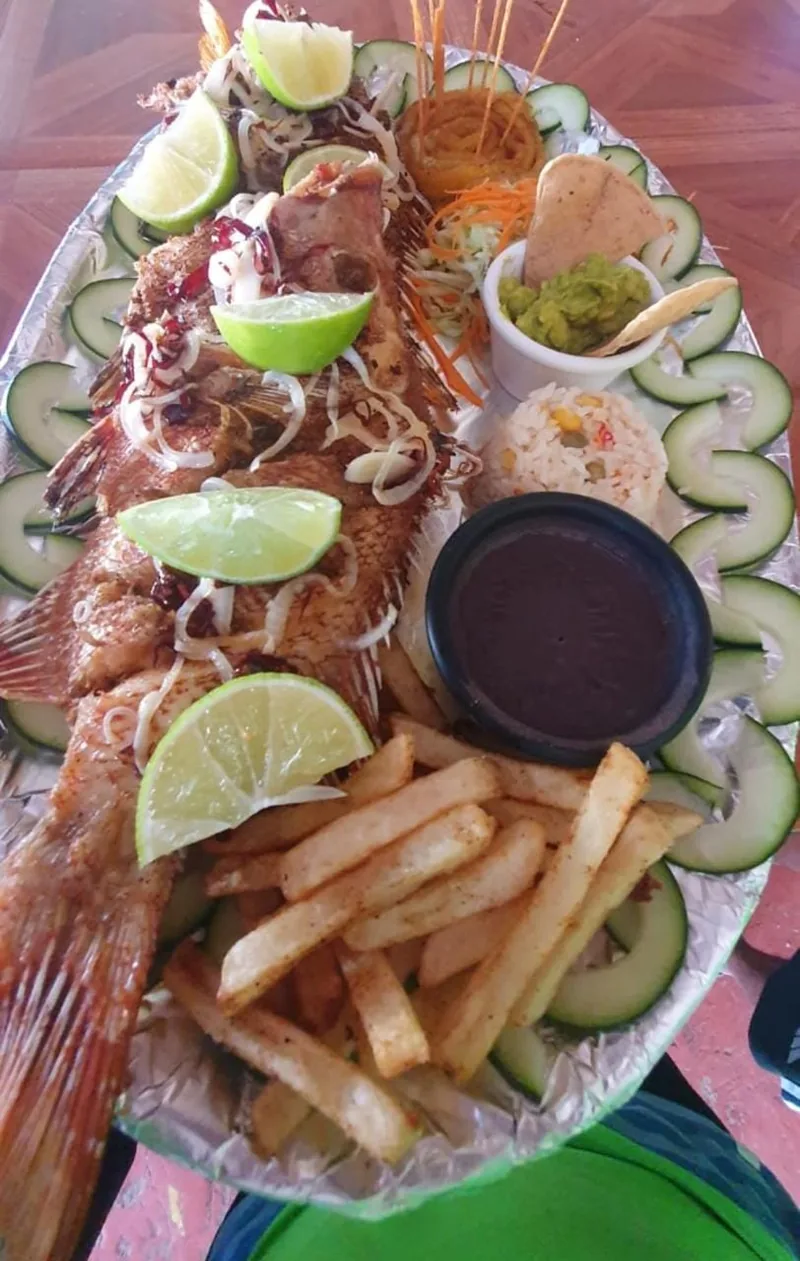 Fried whole fish with french fries, shrimp, lime and salsa at our beachfront restaurant