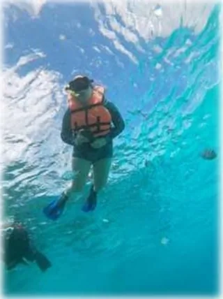 Young snorkeler with life vest exploring the shallow reef